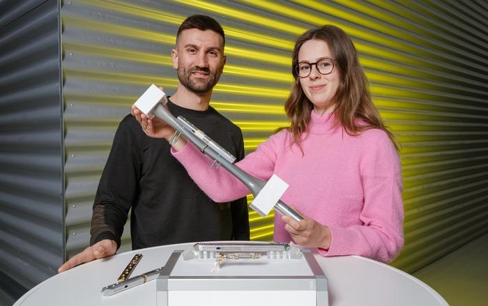 Imagen: Paul Motzki (izquierda) y su equipo presentan en la Hannover Messe un prototipo de implante inteligente que puede controlar el proceso de curación de la fractura y apoyarlo activamente. Floria Wein (derecha) está investigando esta tecnología como parte de su programa de estudios (fotografía cortesía de Oliver Dietze/Universidad del Sarre)